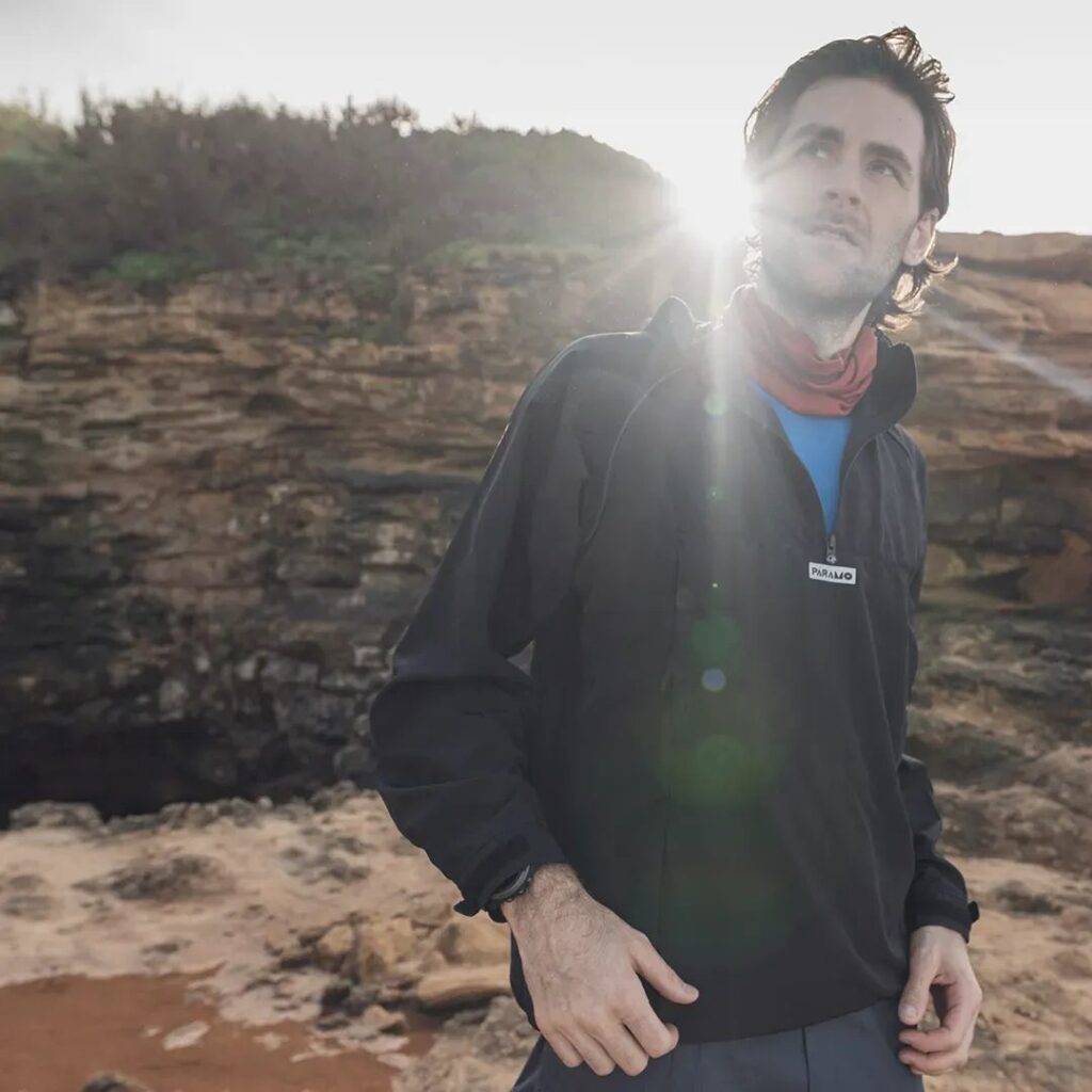 Man wearing the Páramo Fuera Windproof Smock in front of the mountains, sunbeam peaking through 