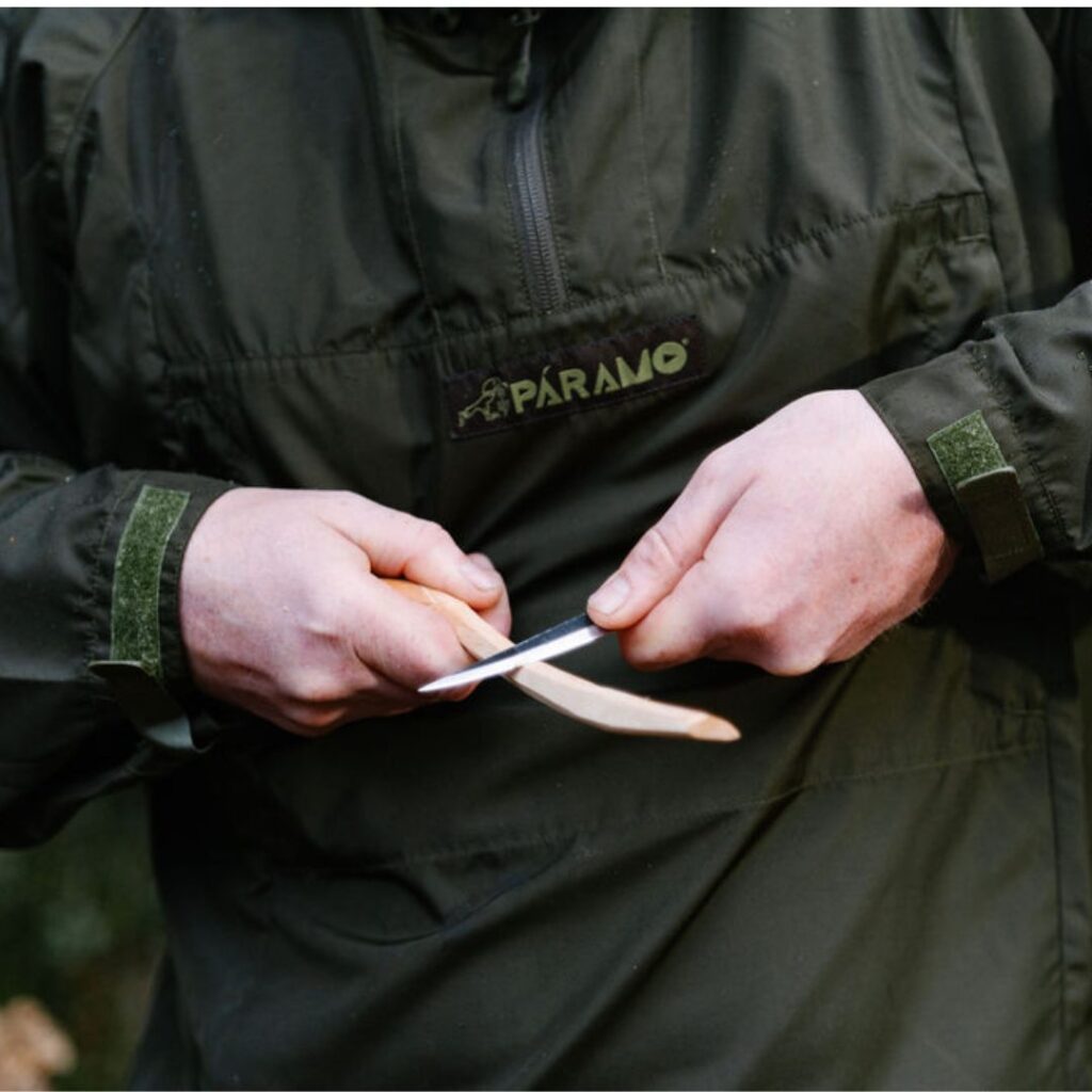 Man in sustainable gear using small tool to shave wood