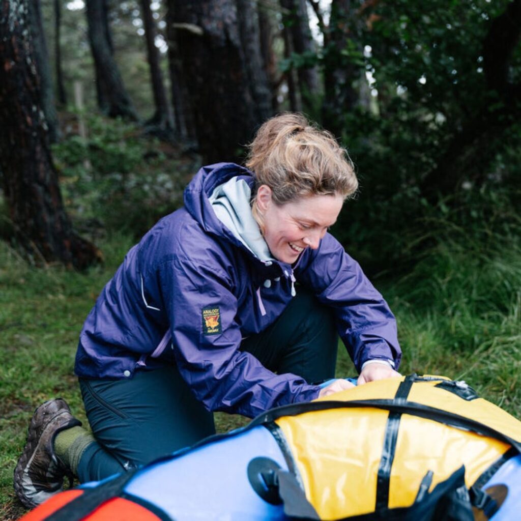 Woman in sustainable gear blowing up a raft 