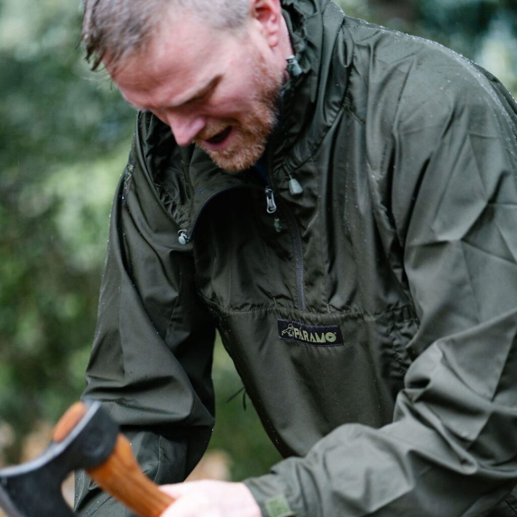 Man wearing the smock with a small woodaxe, chopping 