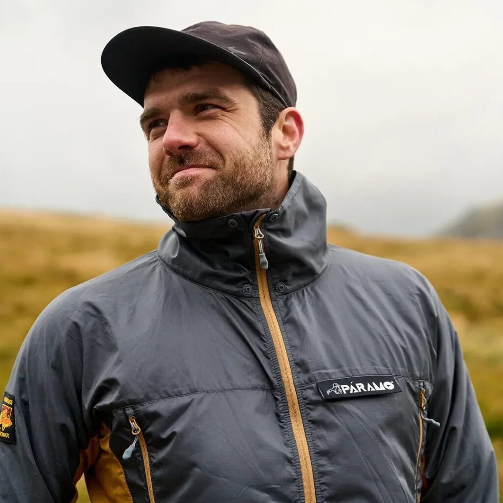 man in cap and Valez Windproof jacket, with grassland in background 