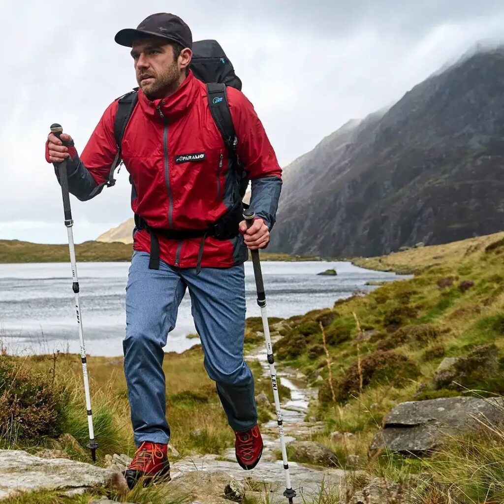 man wearing red jacket, hiking with Nordic poles 